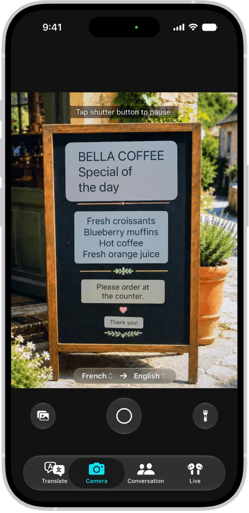 Apple Translate camera view with translated text over a cafe sign and a photo library button at the bottom left